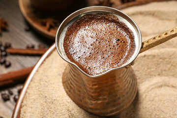 Turkish coffee cooking in sand on wooden background, closeup