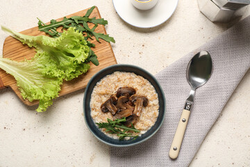 Bowl with tasty oatmeal, fried mushroom and herbs on light background