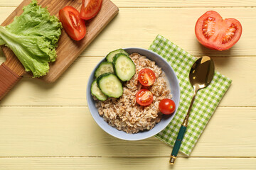 Tasty oatmeal with vegetables on yellow background