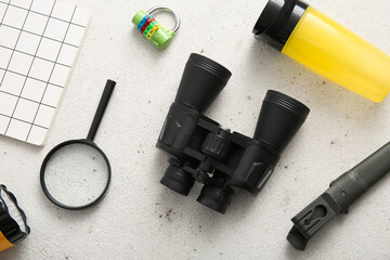 Binoculars and travel items on light background