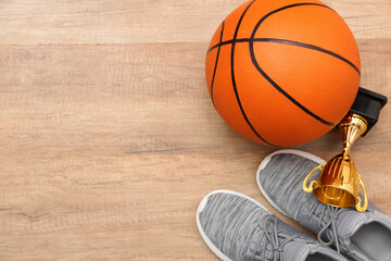 Ball for playing basketball, cup and shoes on wooden background, closeup