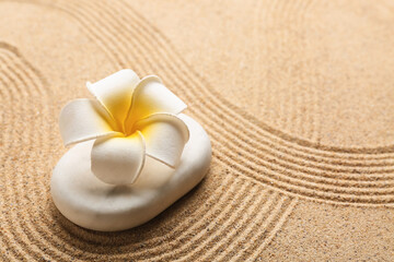 White stone and plumeria on sand with lines. Zen concept