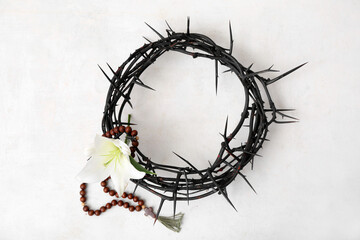 Crown of thorns with lily and prayer beads on white background