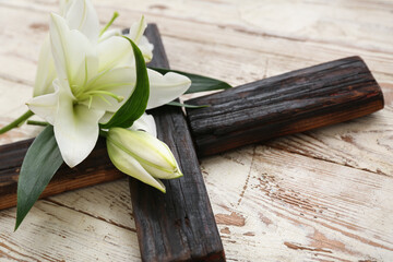 White lily and cross on wooden background, closeup