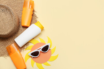 Bottles of sunscreen cream and sunglasses on beige background