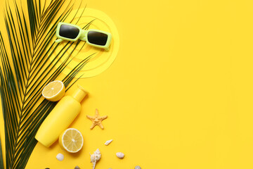 Bottle of sunscreen cream, lemon, sunglasses, paper sun figure, leaf and seashells on yellow background