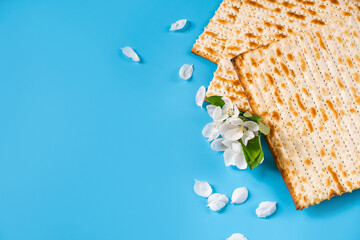 Holiday passover flatlay. Traditional matzah bread and spring flowers on blue background.