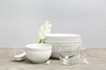 Beautiful tableware and flowers on table near grey wall