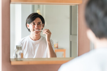 洗面所で歯を磨く若いアジア人男性（口腔ケア・オーラルケア）
