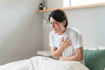 ベッドの上で胸を苦しがる急病の男性（苦しい・発作・心筋梗塞・心臓発作・動悸・狭心症）
