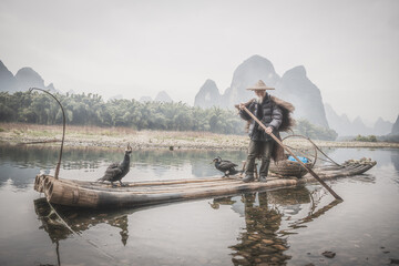 Cormorant fisherman and his birds on the Li River in Yangshuo, Guangxi, China.