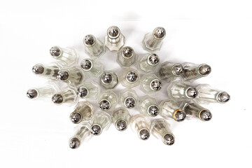 overhead view of a lot of restaurant or diner style salt and pepper shakers on a white table...