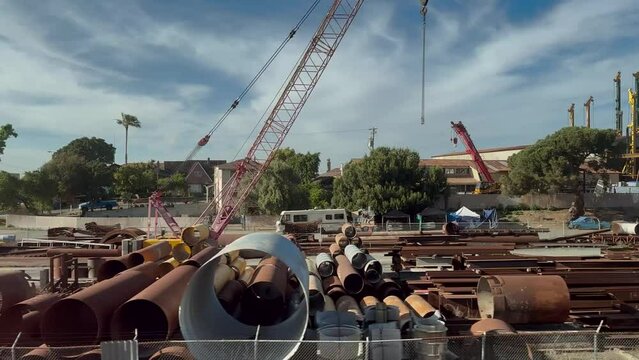 View of a scrapyard with construction material, ranging from wooden pallets to infrastructure-scale pipes. The junkyard helps to dispose of construction waste in an eco-friendly manner.