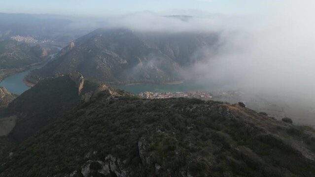 Aerial view of Camarasa in Catalonia. foggy Mountains full of caves and blue river. drone shots flying through the cloudsHigh quality 4k footage
