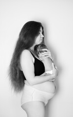 Postpartum woman with her newborn baby. Postpartum body. Body positivity. Real, authentic picture of a woman after giving birth to a baby. Woman holding her newborn daughter. Black and white