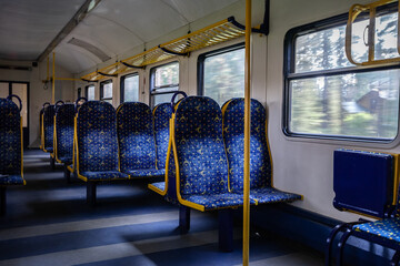 Selective blur on empty Row of seats in refurbrshed latvian regional train with aisle, with nobody russian style on travel in Latvia belonging to Latvian railways with speed blur through the windows. - obrazy, fototapety, plakaty