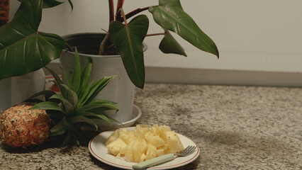 A plate of chopped fresh pineapple fruit as a healthy vegan summer snack on a kitchen countertop...