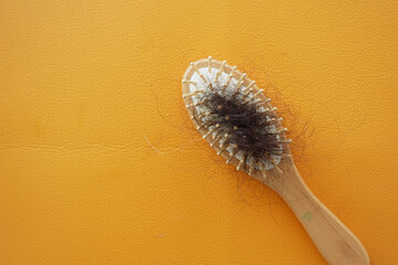 a brush with lost hair on orange color background 