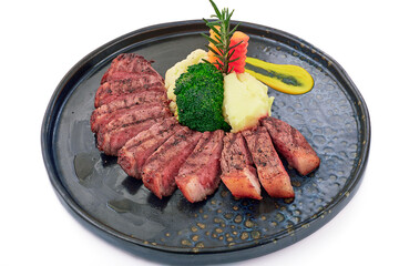 Sliced Black Pepper Beef Steak served with Mashed potatoes, broccoli, carrots and mustard sauce on black plate isolated on white background.