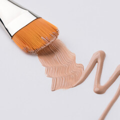 Make up brush and beige tone cream isolated view