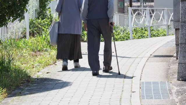 春の街の道路で歩くシニア夫婦の姿