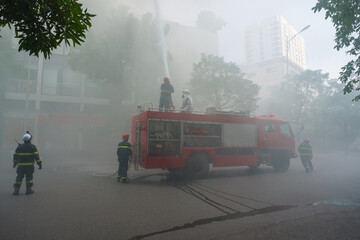 Fototapeta na wymiar Fire trucks and firemen at the training of emergency fire drill in Hanoi
