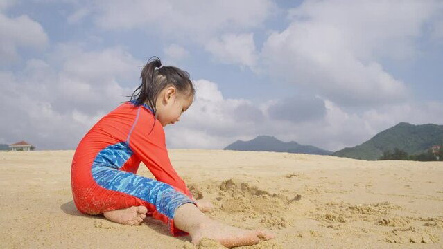 little asian girl playing sand on the beach