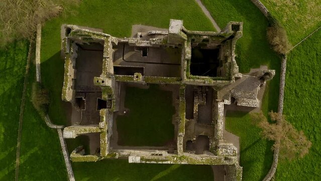 Aerial top down descends on Bective Abbey walls on sunny green Irish day, drone overview