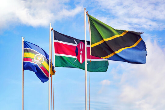 EAC, East African Community flag, flags of Kenya and Tanzania against cloudy blue sky