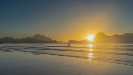 A golden sunset on a tropical island. The ocean waves spread out on the sandy beach. The setting...