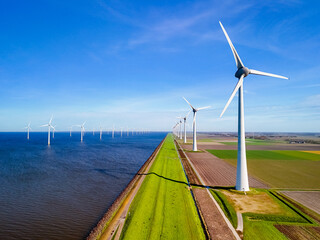  a row of wind turbines gracefully spin next to a body of water in the vibrant season of Spring