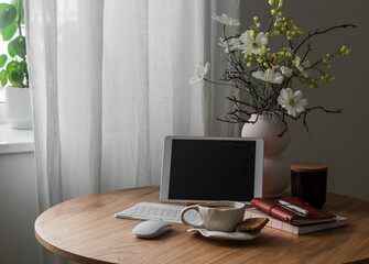 Coffee break in the home office - a cup of coffee, cookies, tablet, a vase of flowers on a wooden round table in the living room - 780248542