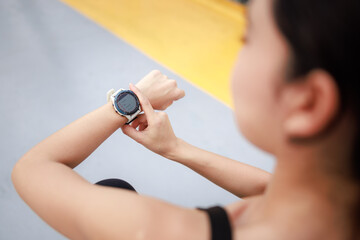 young woman looking down at the timer on her wrist to time before jogging in the morning.