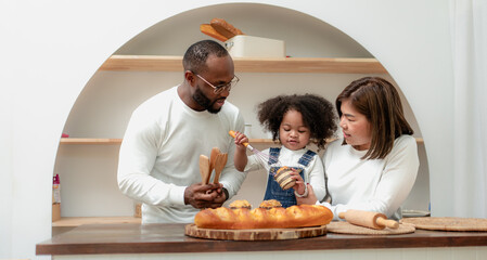 Happy multiethnic family mother father and child having fun playing in cozy kitchen together at home. Playful biracial daughter embracing bonding with dad and Asian mom. Diverse of multiracial people