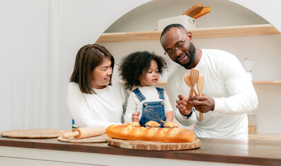 Happy multiethnic family mother father and child having fun playing in cozy kitchen together at...