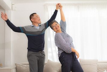 Elderly couple enjoy dancing at home living room relaxing together. Asian senior couple enjoyment lifestyle after retirement. Gray hair husband and wife happy embracing retired pension. Elder family