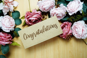Congratulations text message on paper card with flowers border frame on wooden background