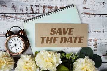 Save the Date text message on paper card with flowers border frame on wooden background