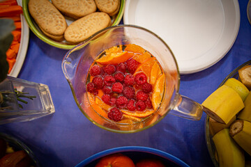 Decanter of chilled refreshing fruit drink with pieces of orange and berries. Close-up.