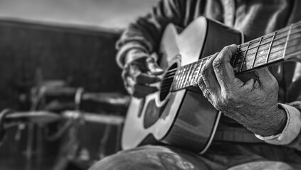 An older male guitarist strums an acoustic guitar  - the camera focuses on his fingers and the fretboard ;the body of the guitar is in soft focus, music, retirement, veteran, experienced, aged, aging, - obrazy, fototapety, plakaty