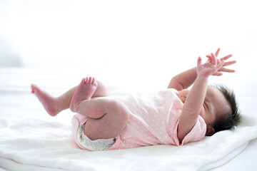 Newborn baby sleeping on white blanket in front of a window acts like she's startled from a bad...