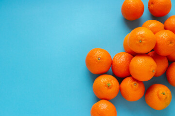 Many fresh orange fruits on right side of light blue background. Vibrant horizontal photo of citrus food with copy space