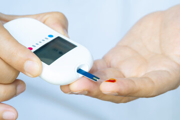 A man draws blood and checks for diabetes and high blood sugar levels with a digital blood sugar...