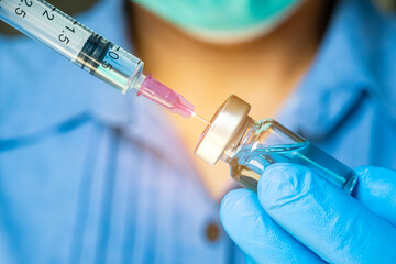 doctor's hand holds a syringe and a blue vaccine bottle at the hospital. Health and medical concepts.	