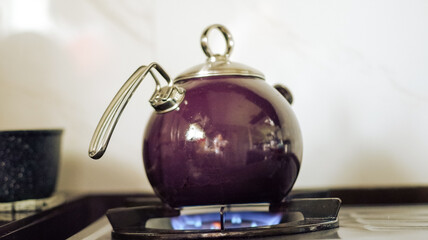 The purple kettle is placed on the gas stove to boil water