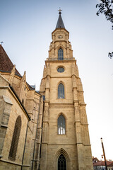 Fototapeta na wymiar Stunning view of a church tower bathed in golden sunset light, showcasing gothic architecture