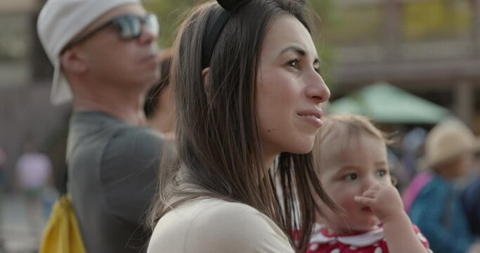 Mother holds toddler girl at parade event