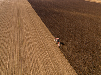 High-angle shot of a tractor with plow tilling the soil, preparing a field for planting