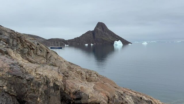 Walking down the hill on the Bear Island. Three-masted schooner in the fjord. Scoresbysund, Greenland.