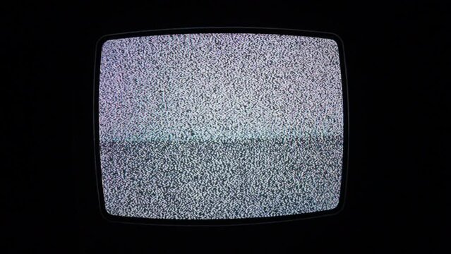 A full screen shot of an old cathode television set showing only white noise iin a dark and isolated room.